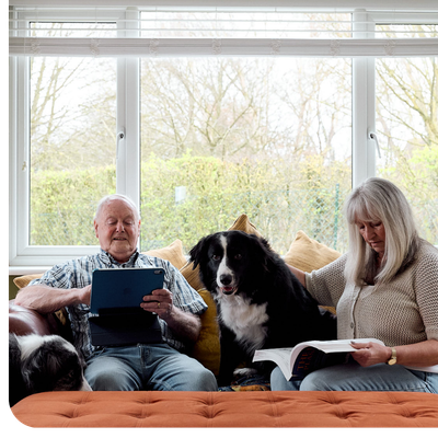 Two PPF members sat reading on the sofa next to the their dog