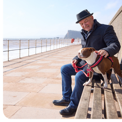PPF member siting on a bench by the sea with his dog