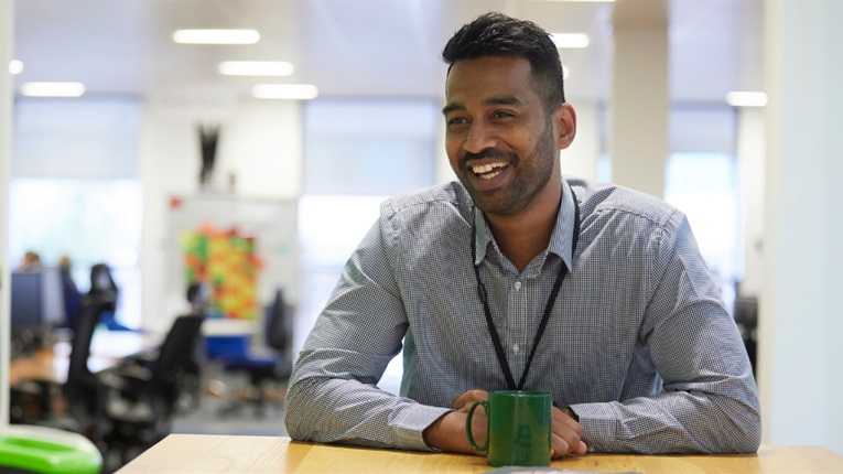 A PPF employee smiling, sitting at a desk in the office