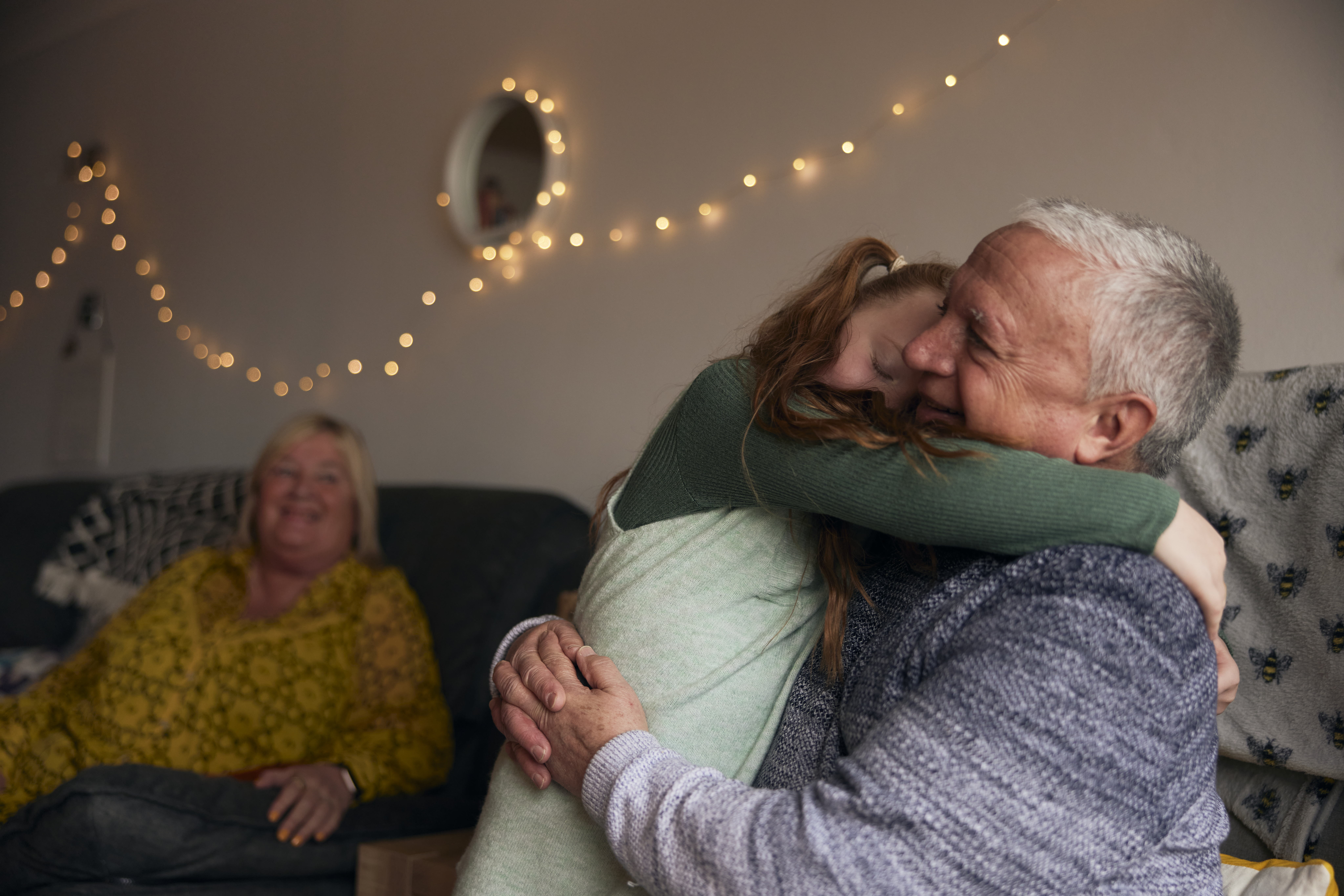 Granddaughter and Granddad hugging in living room