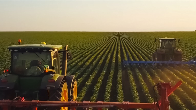 2 tractors cultivating soy beans on a farm